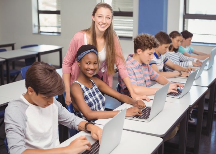 Students using laptop in classroom at school